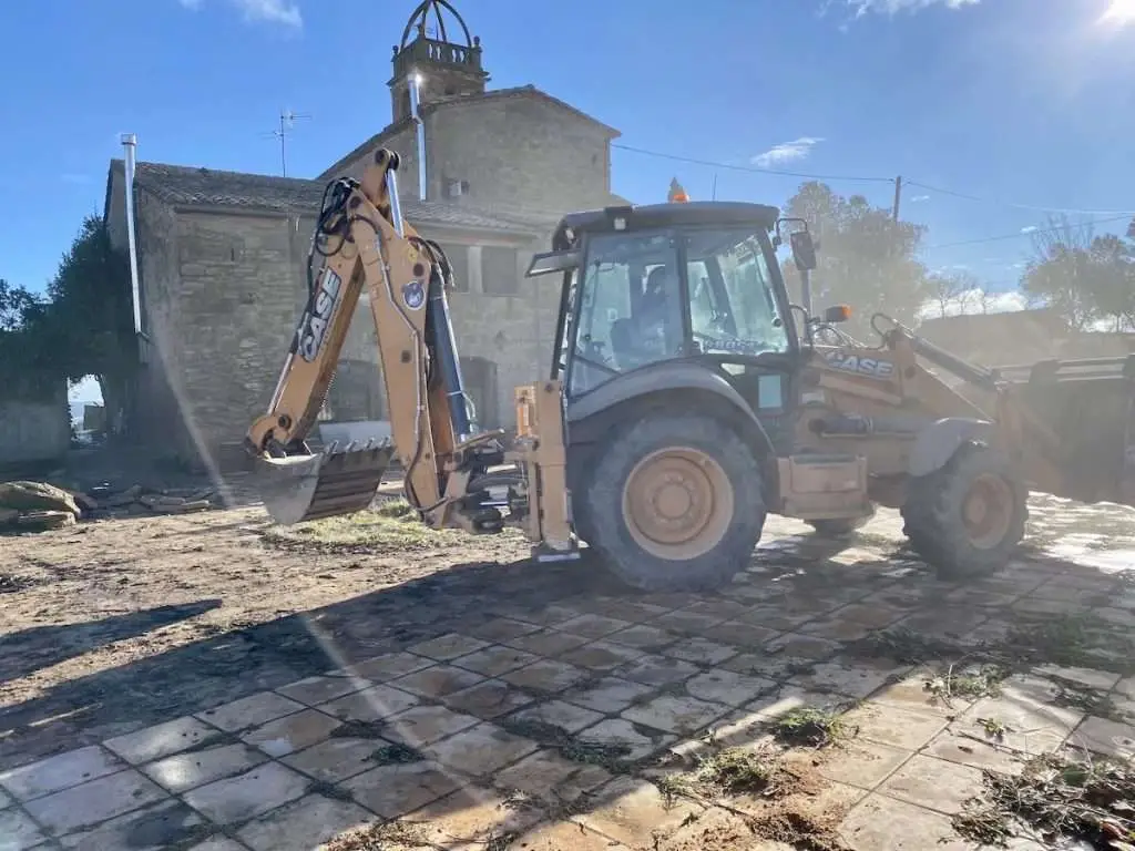 Tractor die de tuin van de Rectoria in Linya leeghaalt.