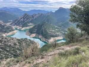 Helder bergmeer omringd door groene heuvels onder een blauwe lucht.