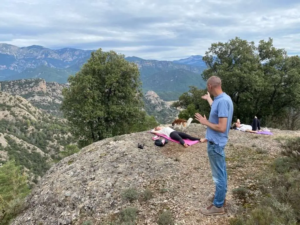 Jarno doet healing bij deelnemers die op een rots liggen met bergen op de achtergrond.