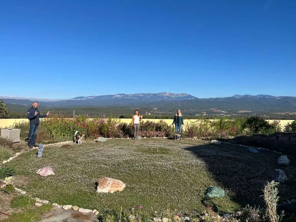 Jarno, Astrid en deelnemers bij krachtcirkel van edelstenen met helder blauwe lucht op de achtergrond.