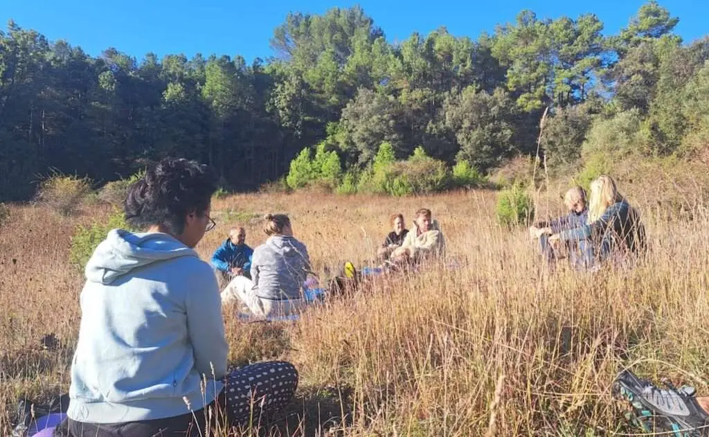 Deelnemers zitten in het veld en krijgen uitleg over energetische werking.