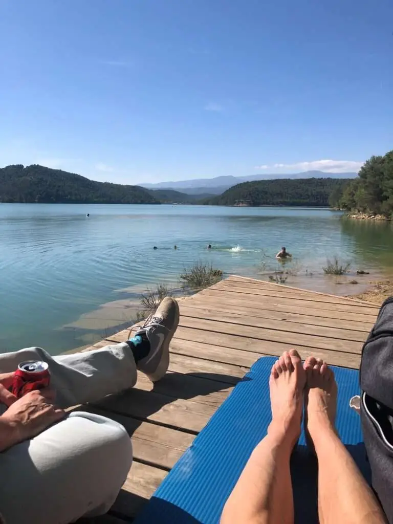 Deelnemers op ligbedden en aan het zwemmen in het meer. Met helderblauwe lucht.