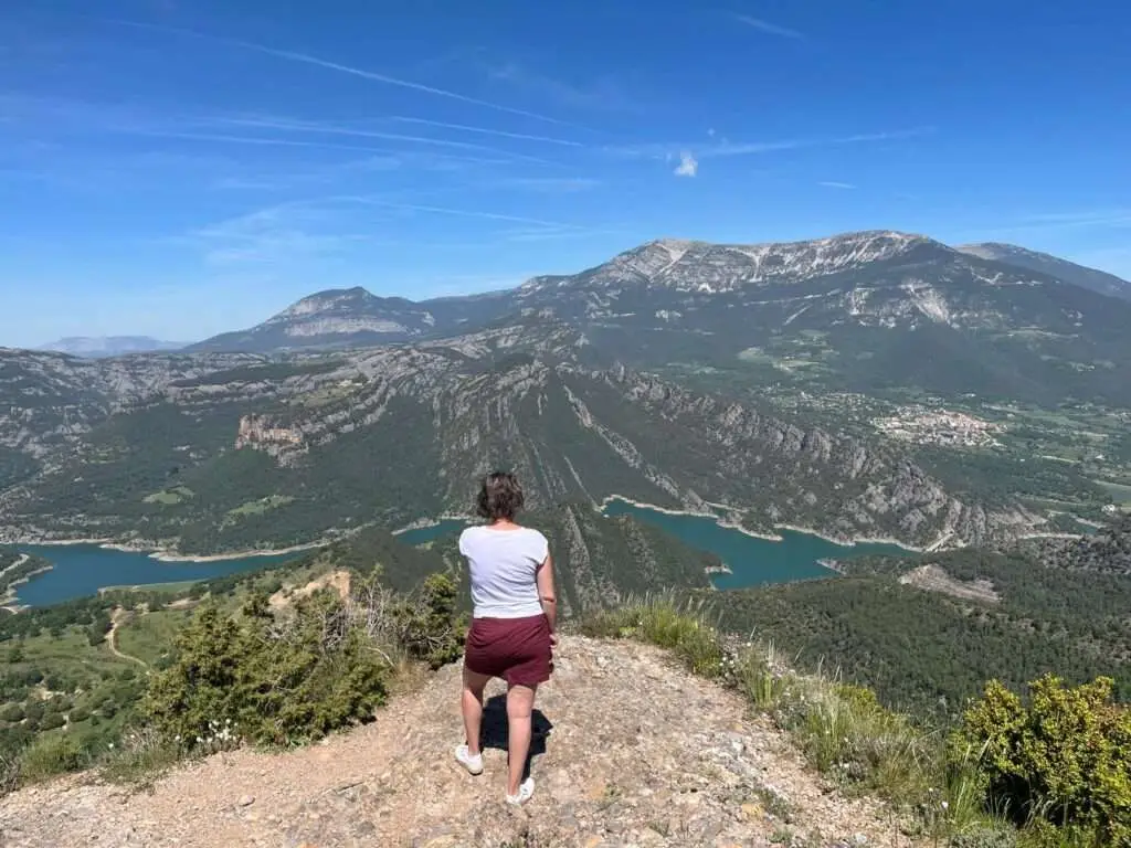 Deelnemer op uitzichtpunt met meer en bergen op de achtergrond.