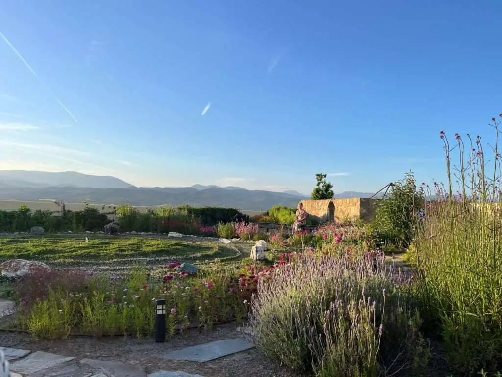Deelnemer zit op bankje bij krachtcirkel van edelstenen bij sralend blauwe lucht.