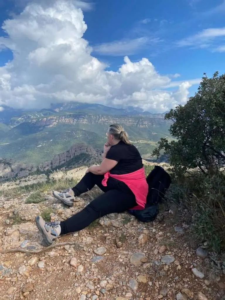 Vrouw die zittend op een bergtop geniet van de stilte en het uitzicht.