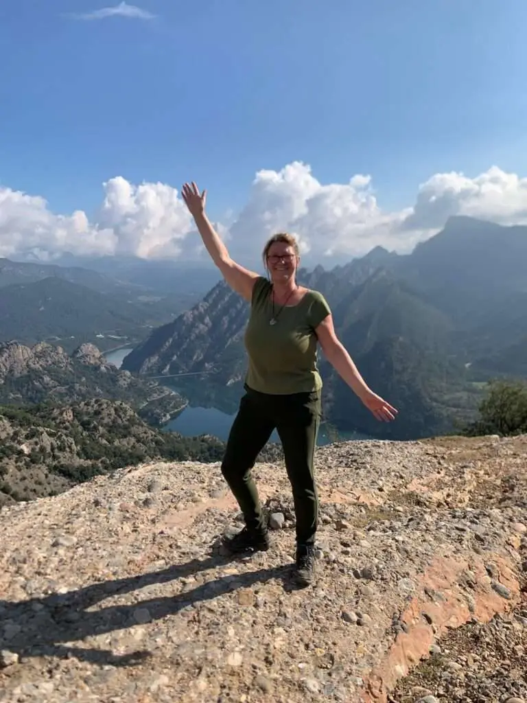Vrouw die blij poseert met berglandschap.