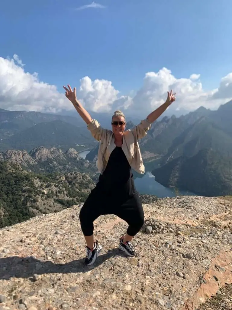 Deelnemer die een vreugdevolle pose maakt aan de rand van een bergrots.