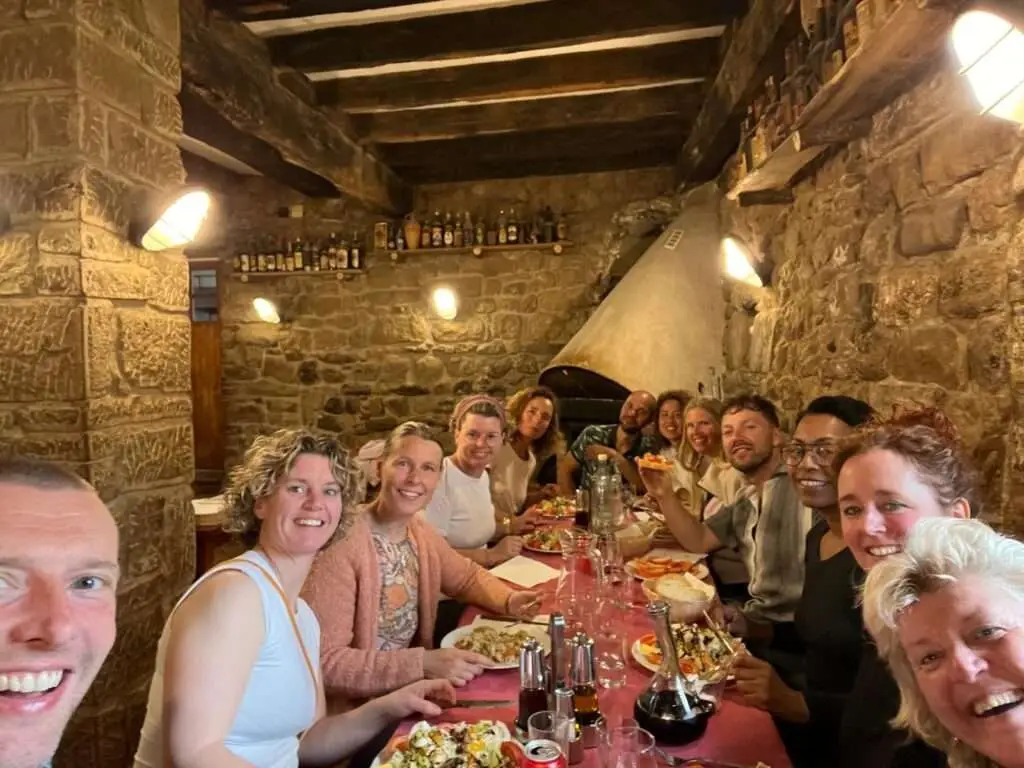 Jarno, Astrid en deelnemers eten gezellig aan een grote tafel tijdens healing holiday.