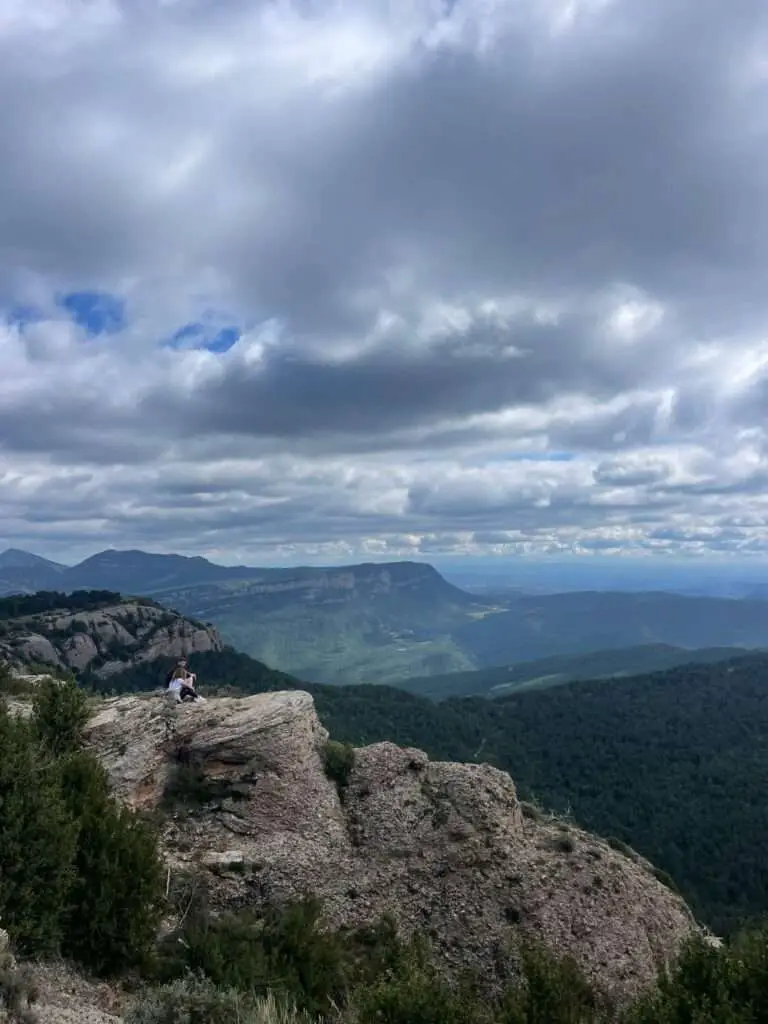 Deelnemers die op een rotspunt zitten en uitkijken over een vallei.