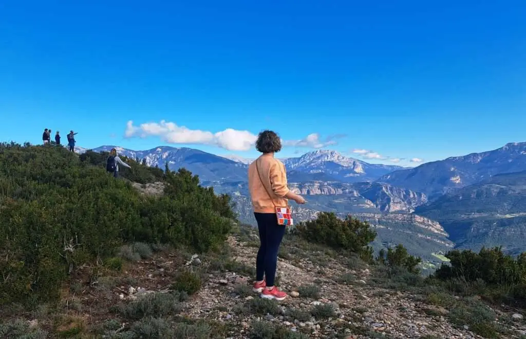 Vrouw aan de rand van een rots met wijd uitzicht over de bergen.