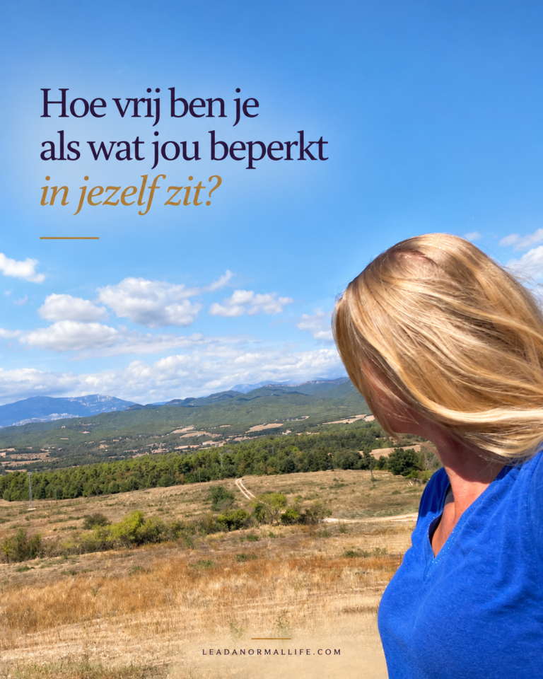 Hoe vrij ben je als wat jou beperkt in jezelf zit? Foto van een vrouw die naar een open weide met op de achtergrond bergen kijkt.